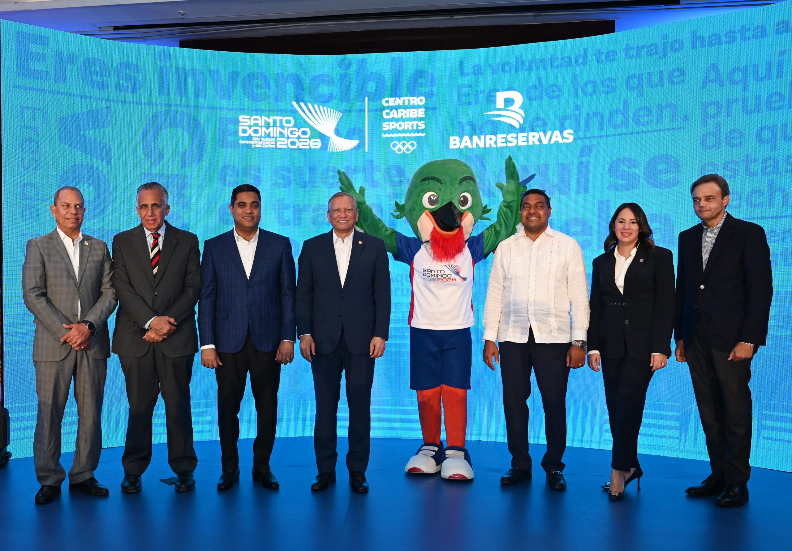 Garibaldy Bautista, Luis Mejía, Kelvin Cruz, Leonardo Aguilera, la mascota Colí, José Monegro, Alieska Díaz y José Ramos en el lanzamiento de la campaña institucional de los Juegos Centroamericanos y del Caribe 2026.